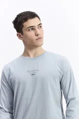 Remera de manga larga color celeste, con escote redondo y estampado frontal con la frase "FAVOR RAINS DOWN + ON ME" y el logo de Mistral.