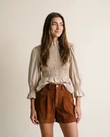 Blusa de algodón con estampado de rayas multicolor, cuello alto con volado, mangas abullonadas con puños fruncidos y cuerpo con frunces elastizados.