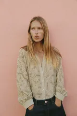 Camisa de cuello solapa con escote en V, manga larga y cierre frontal con botones. Presenta un diseño con bordados perforados en todo la prenda.