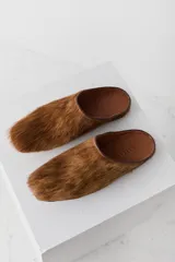 Zueco tipo mule de pelo natural en color camel, con diseño de punta cuadrada y plantilla de cuero.