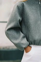 Chaqueta bomber de cuello redondo y manga larga con diseño holgado. Presenta cierre frontal con cremallera, bolsillos delanteros de vivo y acabados elásticos en los puños y el ruedo.