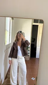 Campera corta de pana con estampado de leopardo, cuello camisero, cierre frontal con botones a presión y dos bolsillos delanteros. Interior forrado con tela a rayas verticales.