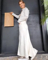 Pollera larga de corte recto en denim color arena, con diseño de cinco bolsillos, cierre frontal con botón y costuras a la vista.