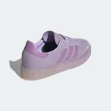 Championes Adidas modelo Sambae, una actualización del clásico Samba con una suela elevada y exterior de cuero nobuk. Presentan las 3 rayas dentadas y puntera en T reforzada. Color violeta claro con suela translúcida.