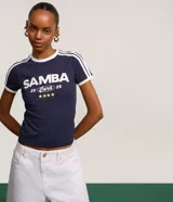 Remera ajustada de algodón color azul marino con cuello redondo y ribetes blancos en el cuello y mangas. Estampado frontal en blanco con el texto "SAMBA 20 Cura 25" y cuatro estrellas doradas debajo.