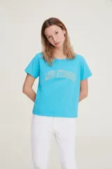 Remera de algodón color azul brillante, con cuello redondo y mangas cortas. Presenta un estampado frontal con el texto 'LEVI STRAUSS' en tipografía estilo universitario.