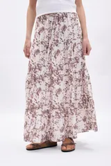 Pollera larga de mujer, con paneles y estampado abstracto en tonos marrones sobre fondo crudo.