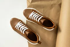 Zapatillas urbanas de cuero, color marrón oscuro, con paneles de gamuza y cuero liso, cordones al tono y suela de plataforma blanca.