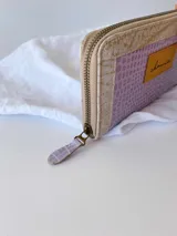 Billetera grande de cuero con cierre metálico perimetral. Presenta un diseño rectangular con textura tipo reptil, monedero interno y espacio para billetes extendidos.
