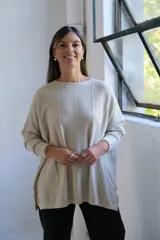 Sweater de punto con hilo lurex color beige, de corte holgado, cuello redondo y mangas largas con puños ajustados. Presenta un diseño con líneas verticales en relieve y aberturas laterales en el ruedo.