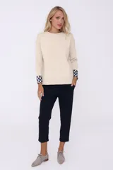 Sweater azul marino de tejido de punto con cuello redondo y puños con diseño a cuadros blancos y negros.