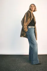 Jean de tiro alto con pierna amplia y corte holgado. Presenta cierre frontal con doble botón, bolsillos traseros de parche y pliegues marcados en el frente y la parte posterior.