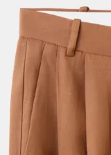 Pantalón de vestir de corte recto y tiro medio, color marrón, con pinzas frontales y bolsillos laterales.