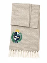 Ruana de tejido de punto en color crudo con diseño de rayas diagonales en relieve, terminación con flecos en el ruedo y escudo bordado en la parte inferior.