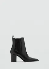 Botin de cuero negro con diseño tipo chelsea, punta fina y taco cuadrado. Cuenta con paneles elásticos laterales y presilla en la parte posterior.