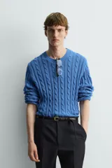Jersey de punto de algodón, color azul, con cuello redondo y manga larga. Presenta un tejido con estructura de trenzas verticales a lo largo de todo el cuerpo y mangas.