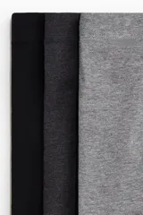 Pack de tres calzoncillos tipo trunk de algodón con elástico revestido en la cintura y frente forrado. Incluye colores negro, gris oscuro y gris claro.