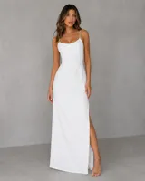 Vestido largo blanco de corte recto y elegante, con tirantes finos decorados con pedrería brillante y tajo lateral profundo en la falda.