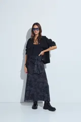 Falda larga de corte fluido con estampado de cuadros en tonos oscuros, rojizos y blancos. Presenta un diseño ligero con terminaciones onduladas en el ruedo.