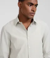 Camisa de sastrería rayada color celeste y blanca, de corte regular, con cuello solapa, cierre frontal de botones y manga larga.