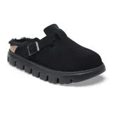Zueco tipo mule de gamuza negra con interior forrado en piel sintética. Presenta una tira ajustable con hebilla metálica lateral y una suela de plataforma dentada de goma negra.
