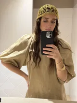 Vestido corto blanco de lino, con cuello redondo con detalle de fruncido y mangas cortas abullonadas. El calce es holgado tipo evasé con un pequeño volante en el ruedo.