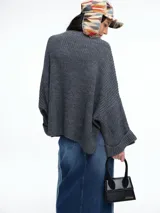 Sweater de tejido de punto color marrón con textura tipo waffle, diseño amplio, hombros caídos y cuello redondo. Presenta un bolsillo frontal aplicado y mangas con puños anchos decorados con botones.