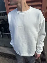 Buzo de corte oversize en color blanco, confeccionado en algodón, con cuello redondo y detalle de logo bordado en el centro del pecho.