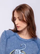 Remera color verde oliva de manga larga con cuello redondo y costuras a la vista. Estampado frontal de un tigre dentro de un círculo.