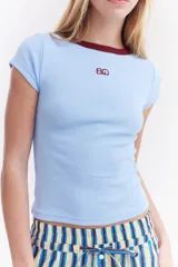 Top de canalé amarillo con cuello redondo y ribetes en color bordo, mangas cortas y detalle de logo bordado en el pecho.