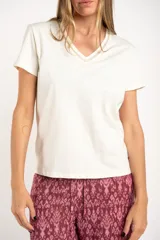 Remera de algodón peinado color blanco, con escote en V y detalles de lurex dorado en el borde del escote. De manga corta y corte ajustado.