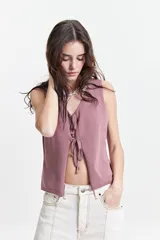 Chaleco tejido color lila con escote en V y lazo doble al frente.