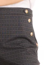 Pantalón de corte recto y largo al tobillo, confeccionado en gabardina elastizada con estampado cuadrillé. Presenta cintura alta tipo pull-on, bolsillos simulados en la parte frontal y detalle de botones decorativos dorados en los laterales de la cintura.