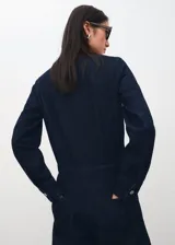 Mono largo de denim color azul oscuro, con cuello redondo, cierre frontal con botones metálicos, mangas largas y corte recto en las piernas.