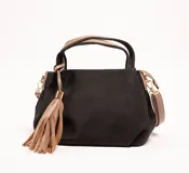 Cartera negra con textura tejida, doble asa corta y correa larga desmontable. Incluye un charm de flecos color beige.