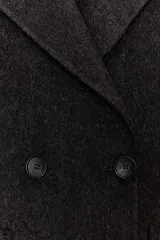 Abrigo largo cruzado color gris oscuro, confeccionado con lana. Presenta cuello solapa, manga larga, bolsillos delanteros de plastrón y cierre frontal con botones.