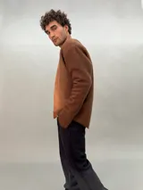 Buzo de lana merino afieltrada color negro con estampado abstracto plateado en el frente. Tiene cuello redondo y puños con forma que cubre levemente la mano. Es más largo en la parte inferior trasera.