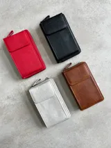 Cartera portacelular con correa larga, cierre con cremallera y solapa con broche imantado.