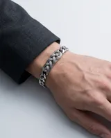 Pulsera de acero inoxidable con eslabones de cadena y un detalle central de diseño trenzado tipo nudo celta.