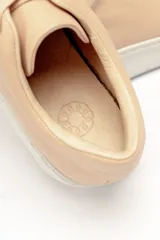 Zapatillas color beige claro, con capellada de cuero suave y acolchado, forro y plantilla de cuero vacuno, y suela de EVA. Tienen una plataforma de 3.8 cm en la parte trasera y 3.2 cm en la delantera.