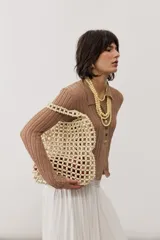 Cartera tipo shopper confeccionada en cuentas de madera de color crudo, con diseño de red y asas de hombro.