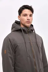 Campera tipo parka de gabardina con capucha ajustable mediante cordones. Presenta cierre frontal metálico, interior capitoneado y parche decorativo en la manga.