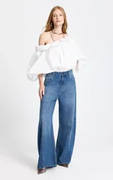 Jean de tiro alto con corte wide leg, confeccionado en denim azul clásico. Presenta costuras verticales frontales que estilizan la silueta y un diseño de pierna ancha.