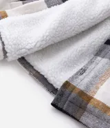 Campera de franela a cuadros con forro interno de sherpa, cierre frontal con botones, cuello camisero y bolsillos frontales en el pecho.