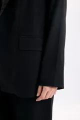 Blazer sastrero de lino color negro, con solapas clásicas, bolsillos delanteros con solapa y diseño de corte recto.