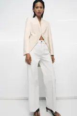 Jeans blancos de tiro alto con diseño wide leg, detalle de nervio delantero y pespuntes marcados a contraste. Presenta cierre frontal con cremallera y botón, y cinco bolsillos.
