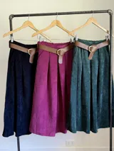 Falda midi de corte clásico confeccionada en corderoy, con cintura elastizada, diseño de tablas y bolsillos laterales. Incluye un cinturón desmontable en color marrón.