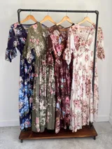 Vestido midi de estilo campesino confeccionado en organdí con estampa floral chintz de estilo romántico. Presenta escote en V cruzado, cintura completamente elastizada y falda larga con volados en niveles. Las mangas son tres cuartos con volados en los puños.