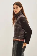Campera híbrida con frente acolchado tipo puffer en color negro y mangas de tejido liso al tono. Presenta cuello alto, cierre frontal y diseño entallado.