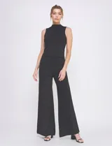 Pantalón palazzo de tiro alto color negro con brillo, confeccionado en tejido lurex. Tiene pretina ancha elastizada.